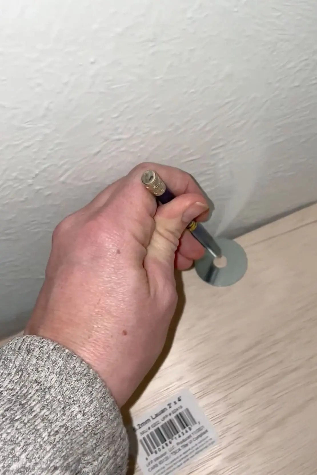A DIYer marks a cut line for a crooked wall, using a washer as a guide.